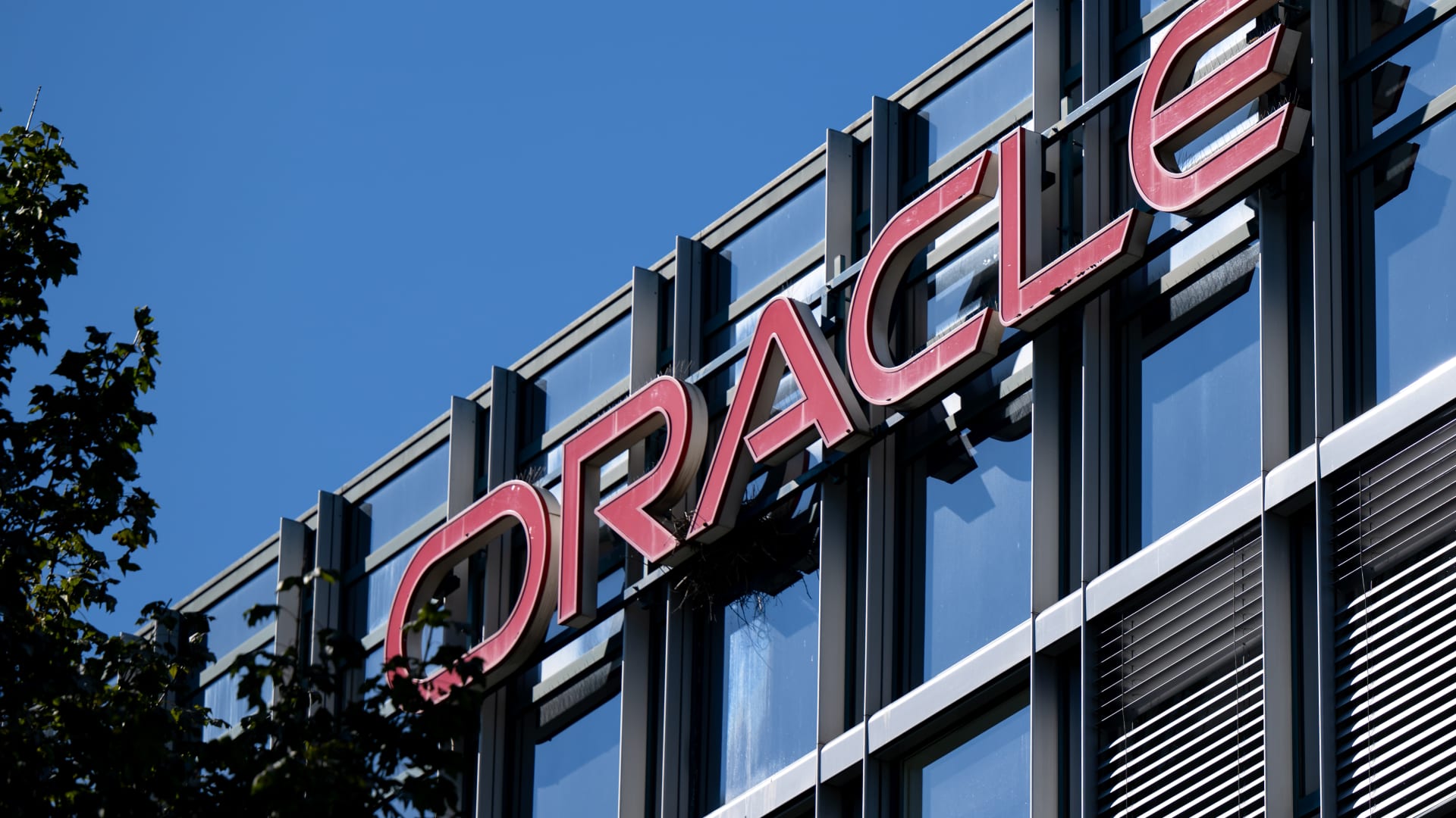 Oracle logo mounted on a modern glass office building under a clear blue sky