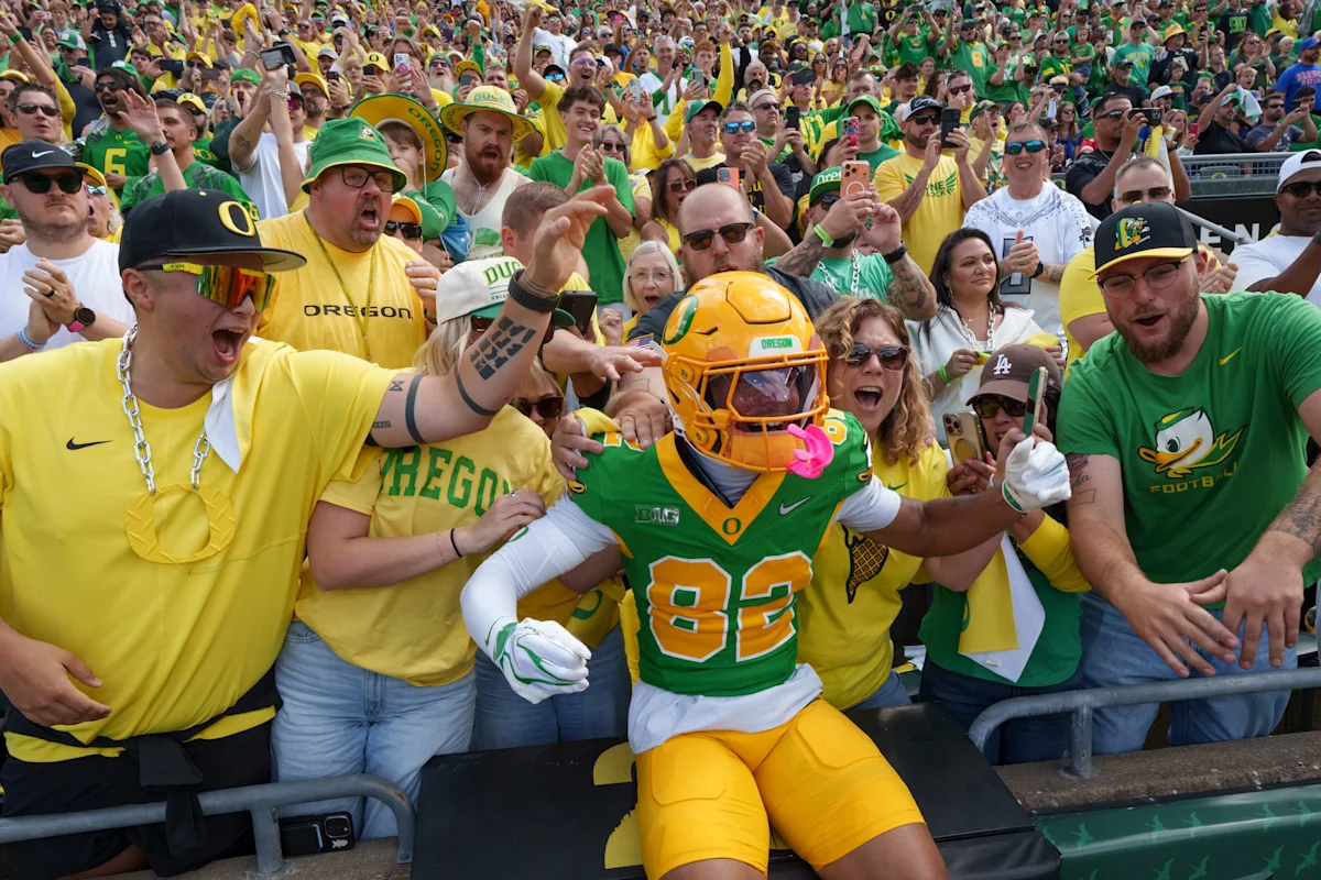 Oregon Ducks fans cheer beside a football player in green and yellow uniform