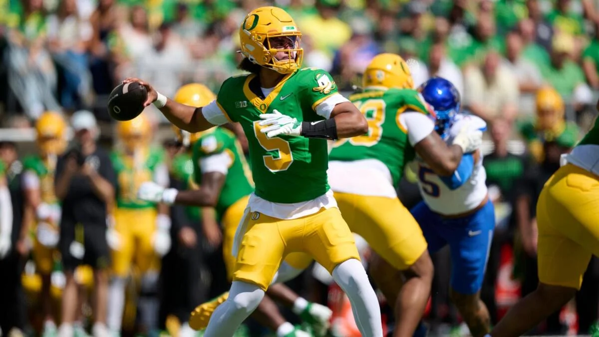 Oregon quarterback in green and yellow prepares to throw during a college football game