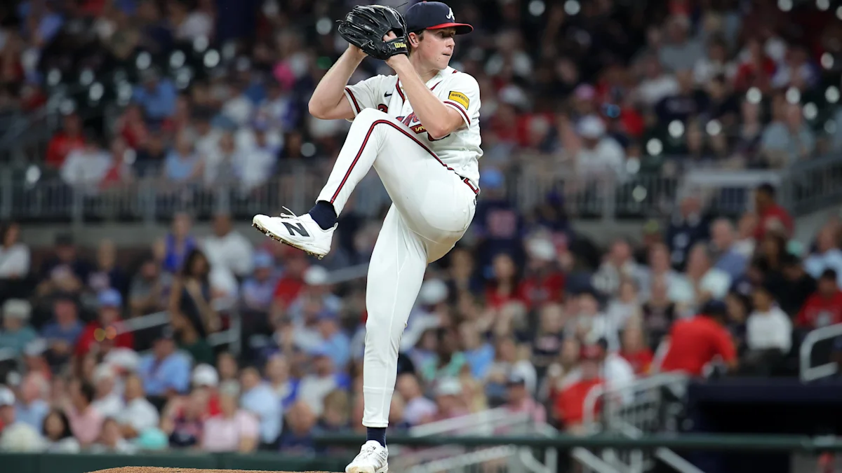 A pitcher in a white uniform lifts his leg during a delivery on the mound.