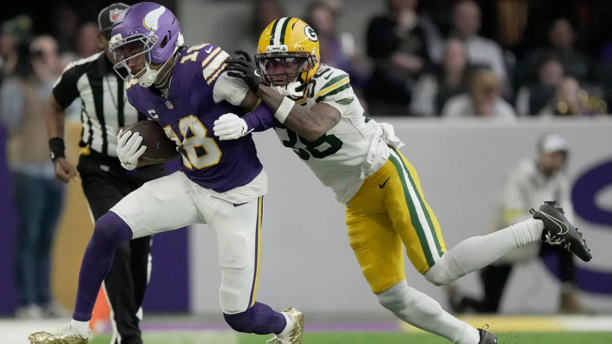 Vikings ball carrier runs as a Packers defender reaches to tackle him.