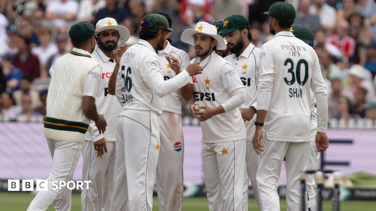 Pakistan cricket players in white Test uniforms gather together on the field during a match