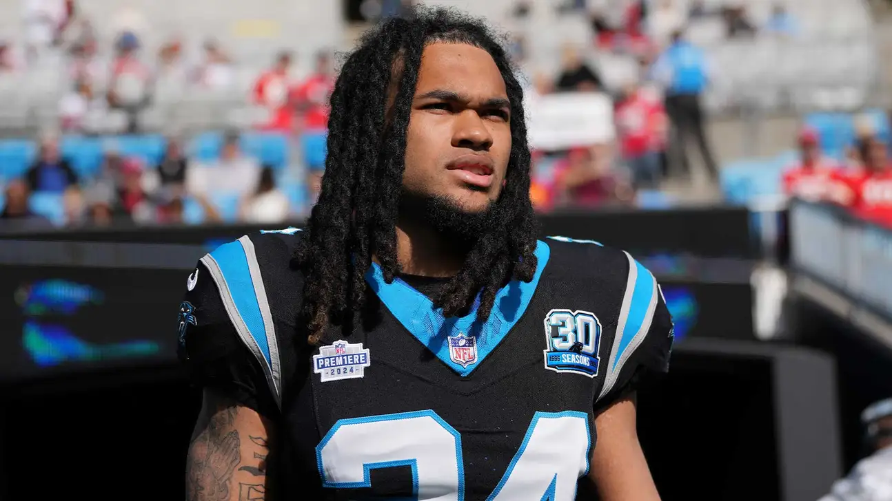 Carolina Panthers football player with dreadlocks stands on the sideline in uniform