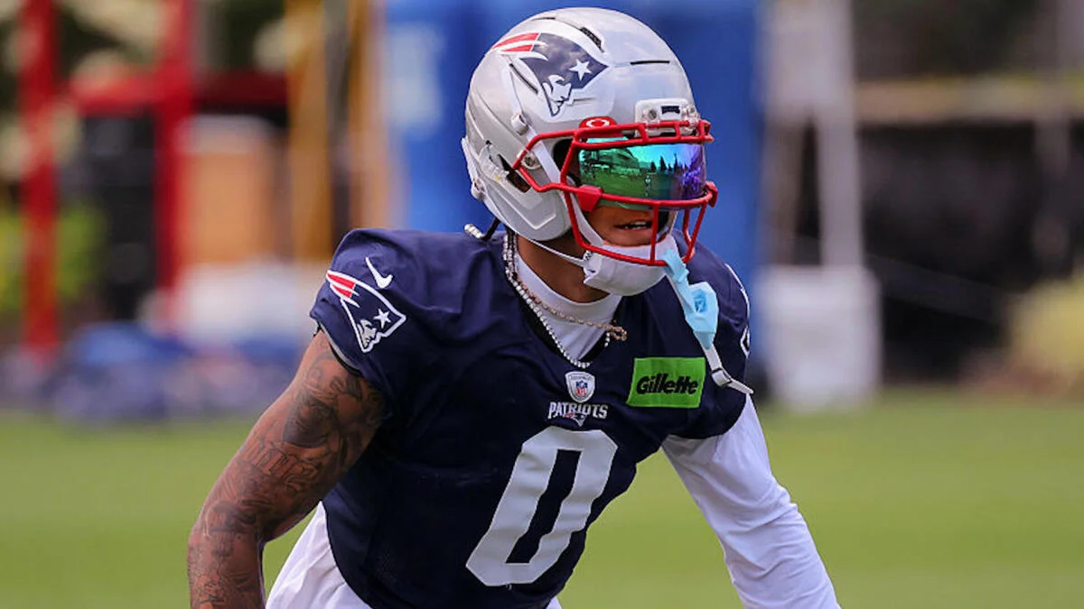 Patriots cornerback in helmet and uniform prepares for a play during football practice