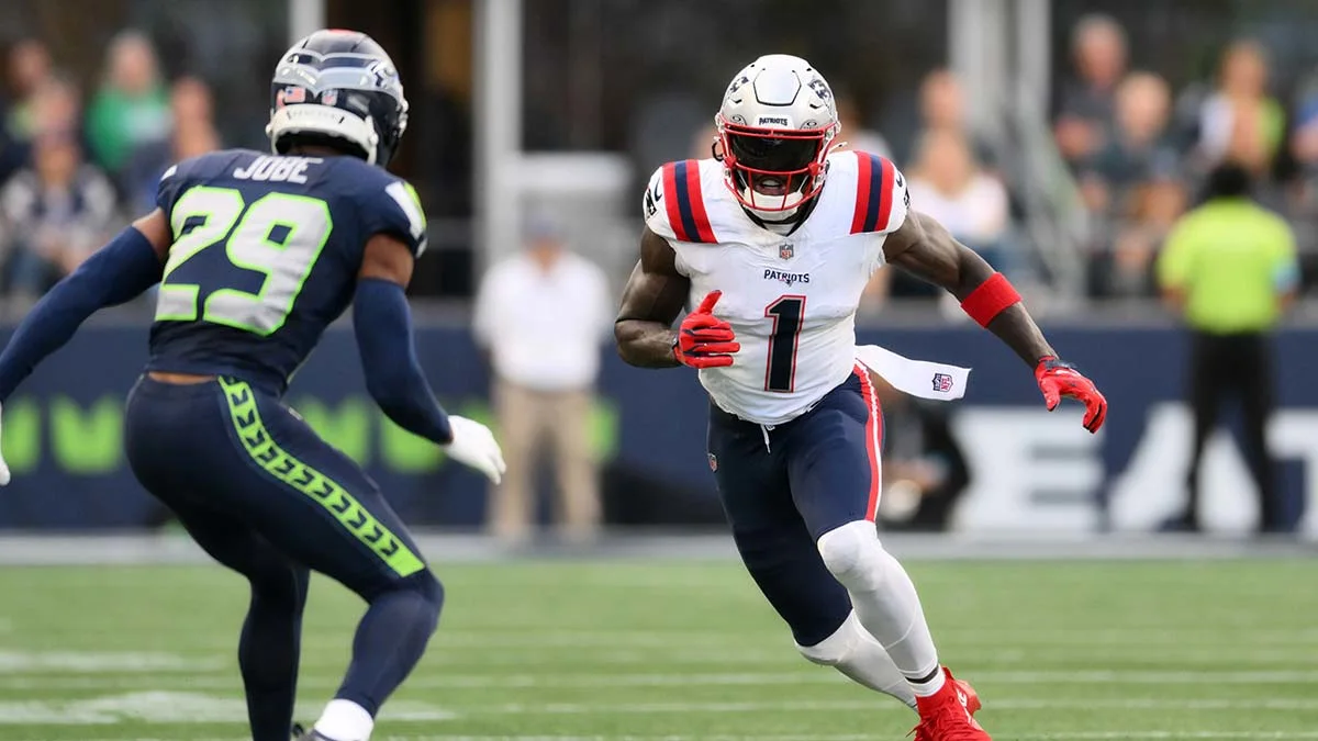 Patriots receiver in white uniform runs with the ball as Seahawks defender closes in