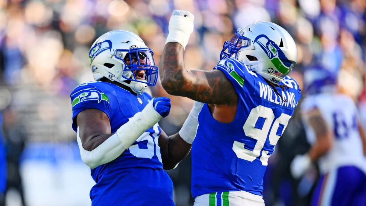 Two Seattle Seahawks players in blue uniforms celebrate during a football game.