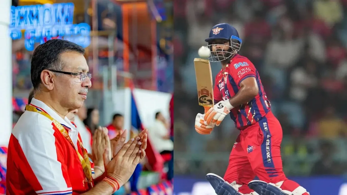 A cricket official claps beside a batsman in red and blue kit during a match.
