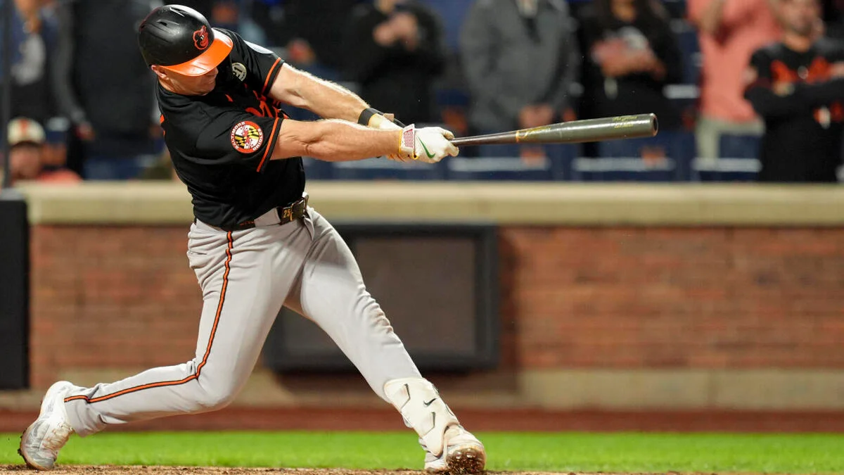 Baseball player in Orioles uniform swings a bat during a game.