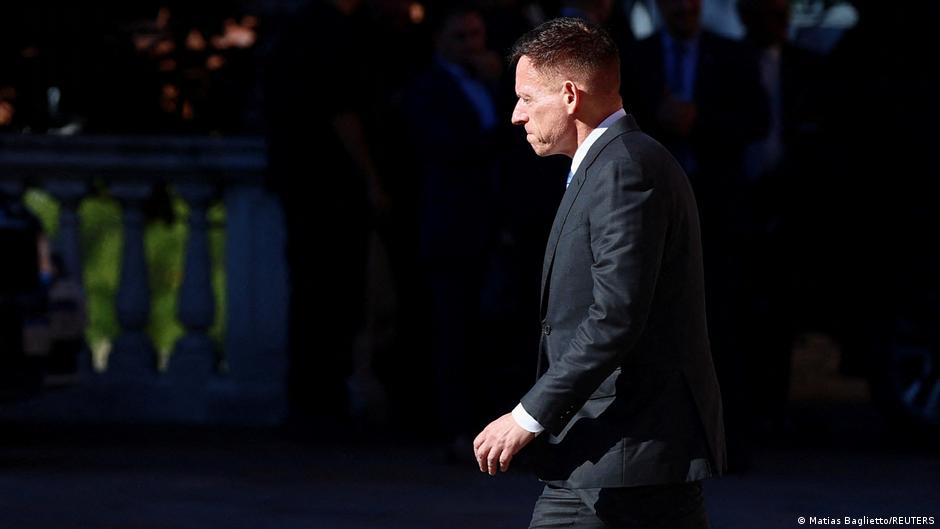Profile view of a suited man walking through a dimly lit event venue