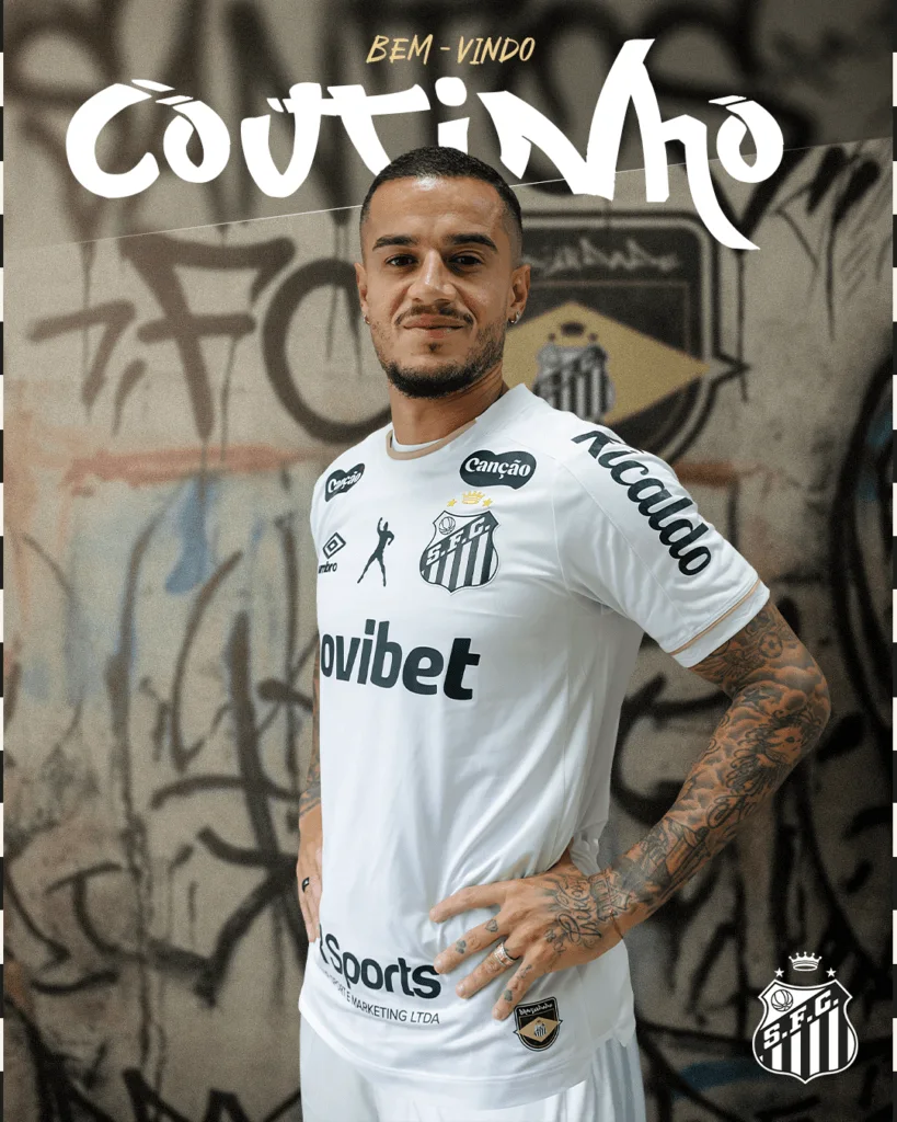 Footballer wearing a white Santos FC jersey poses in front of a graffiti-covered wall.