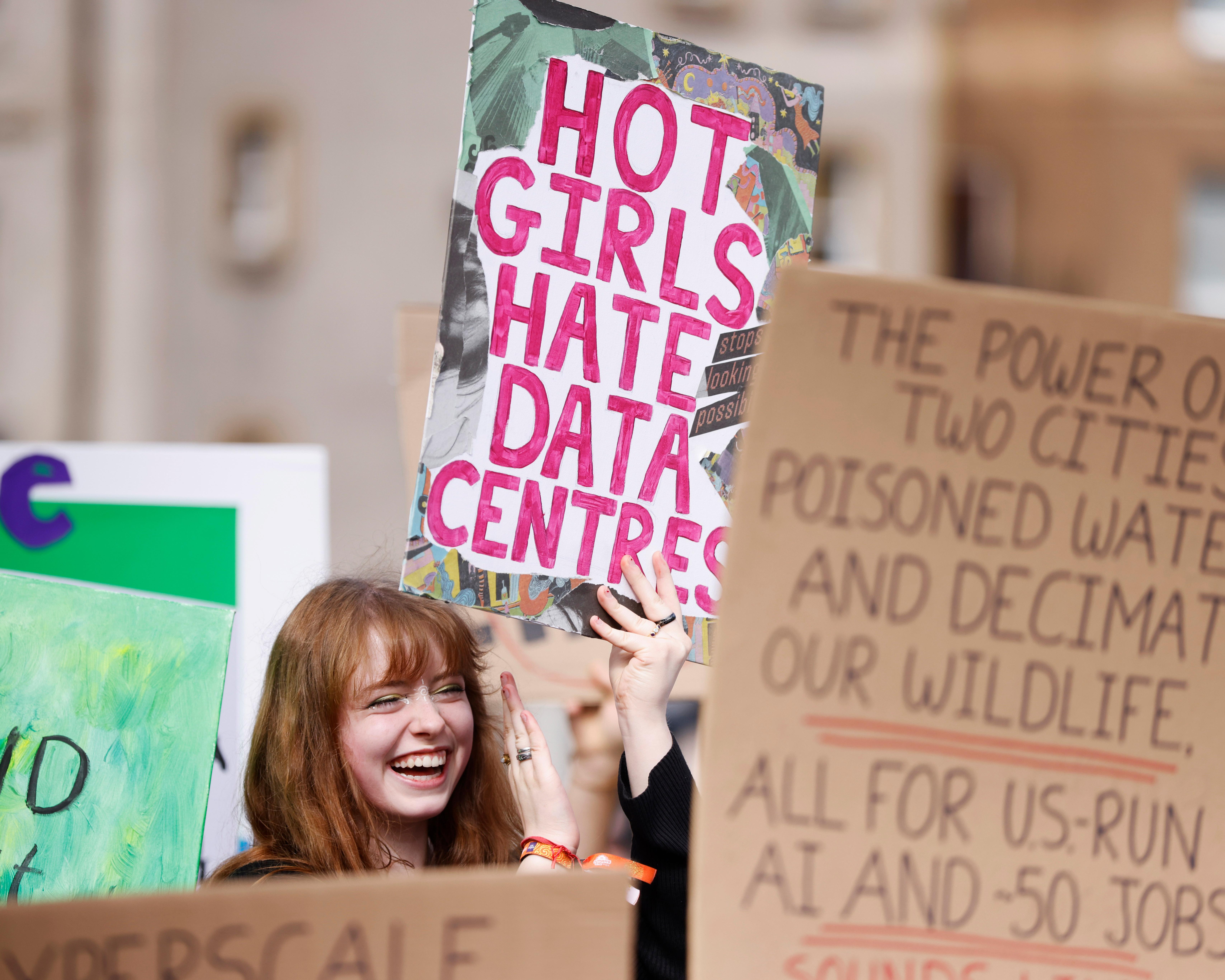 Young protester holds a handmade “Hot Girls Hate Data Centres” sign among climate protest placards.