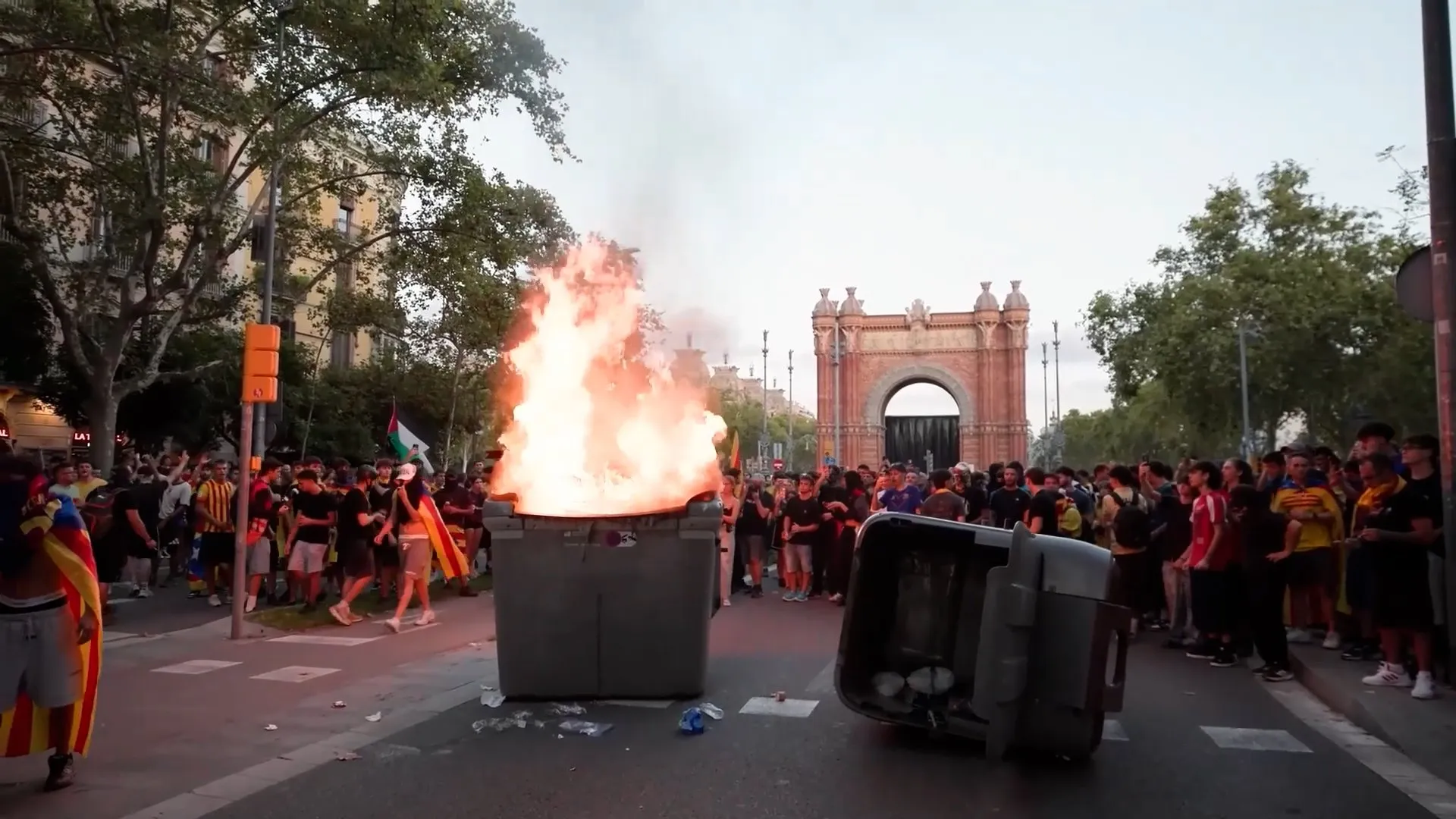 Crowd gathers around a burning rubbish bin near Barcelona’s Arc de Triomf.