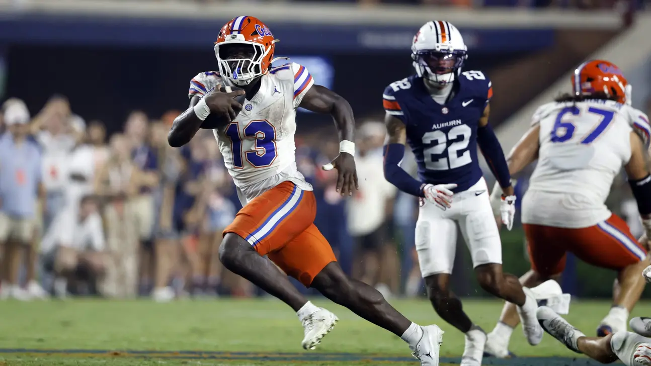 Florida player number 13 runs with the football as Auburn defender number 22 gives chase.