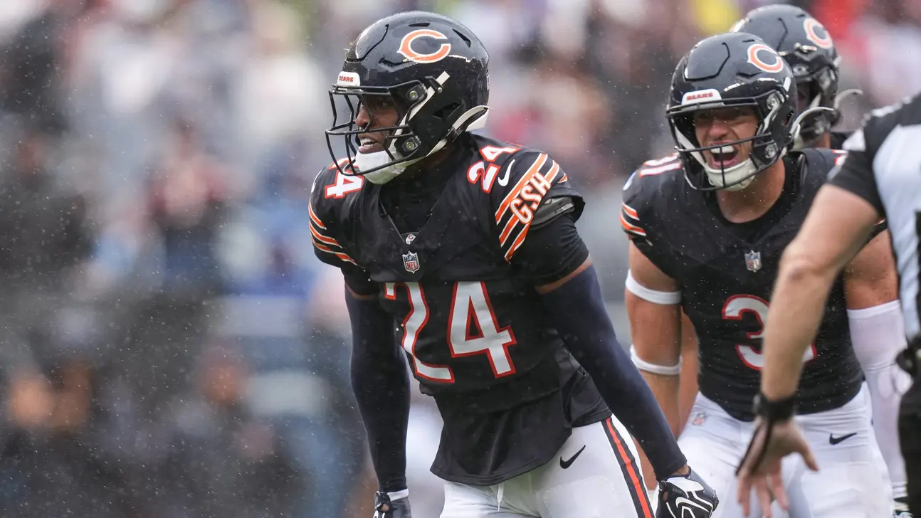 Chicago Bears players in black uniforms gather on a rainy field during a game.