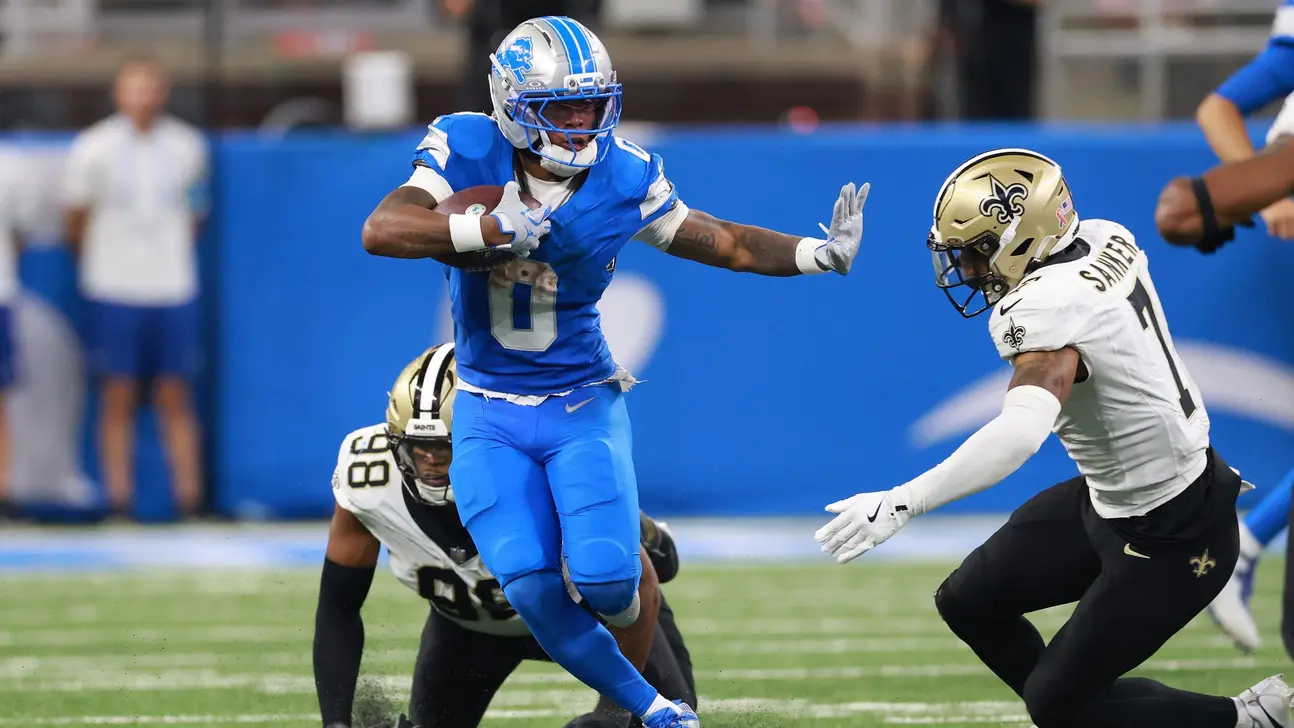 A Detroit Lions player runs with the football as New Orleans Saints defenders pursue him.