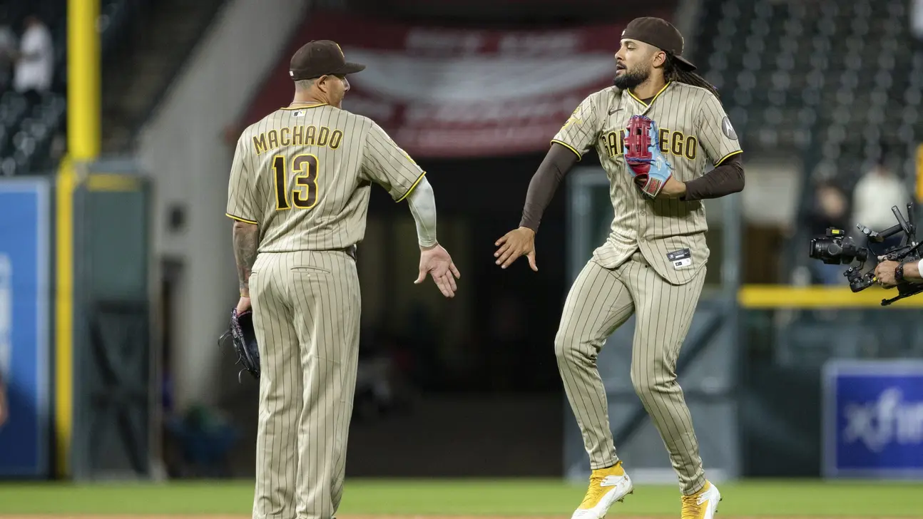 Two San Diego Padres players exchange a celebratory low-five on the field.