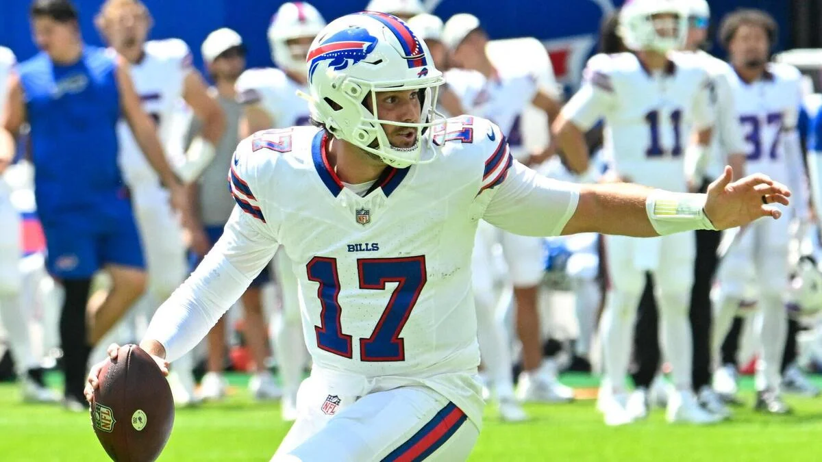 Buffalo Bills quarterback in white uniform extends his arm while holding a football.