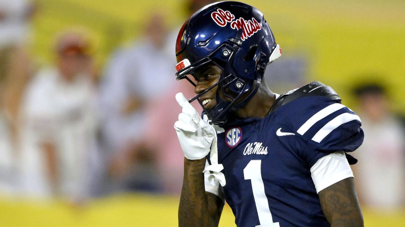 Ole Miss football player in navy uniform and helmet smiles and raises a gloved finger during a game