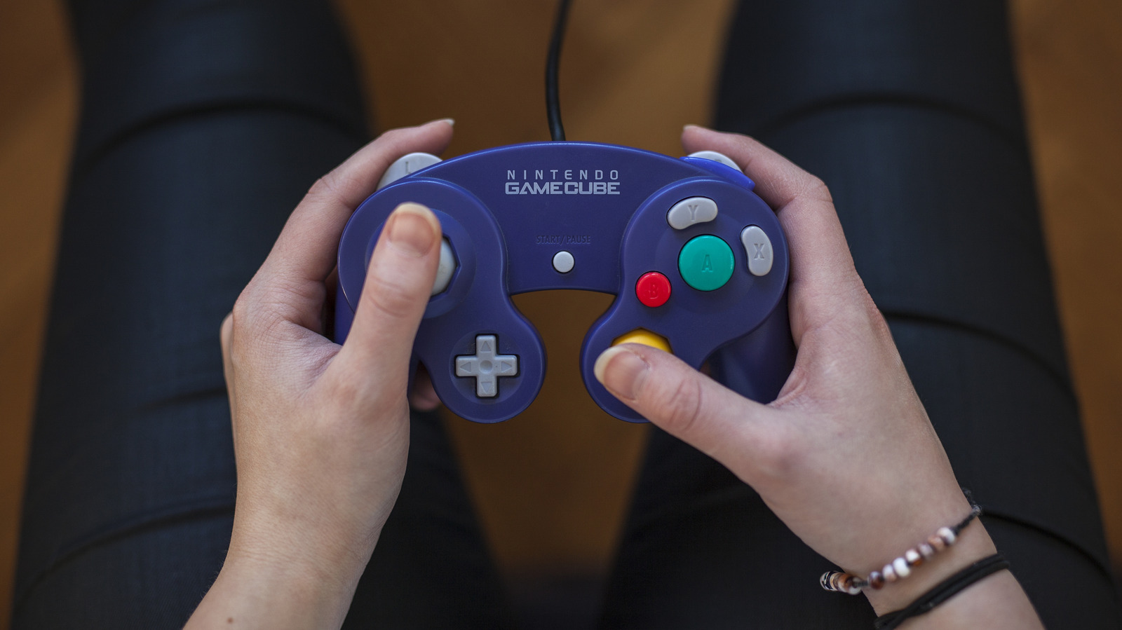 Hands holding a purple Nintendo GameCube controller while playing a video game
