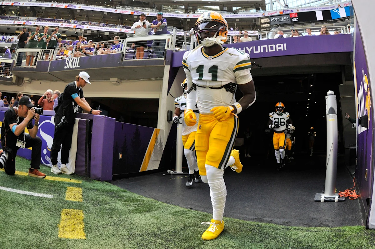 Football player wearing number 11 runs onto the field from a stadium tunnel.