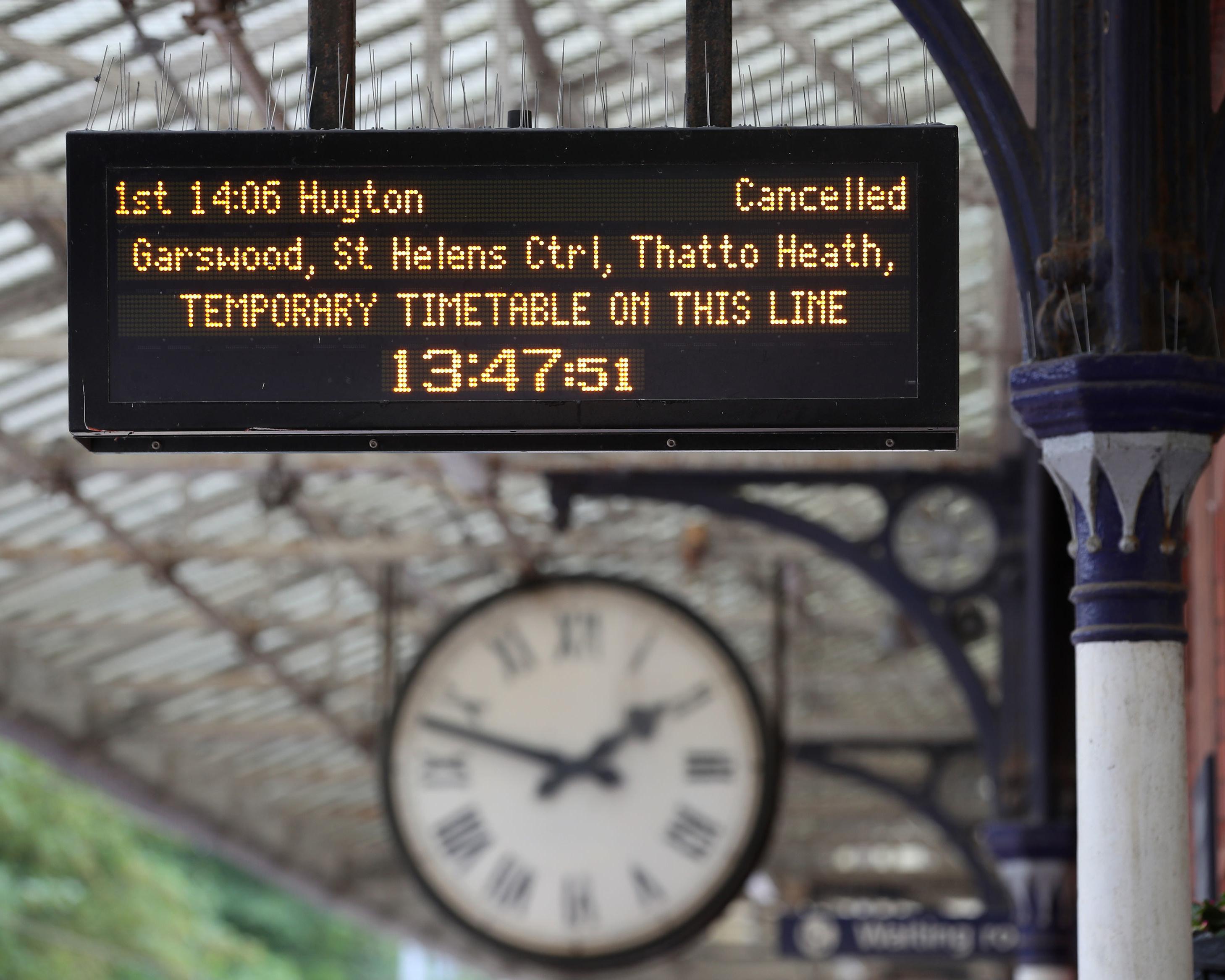 Electronic railway departure board displays a cancelled train and temporary timetable information.