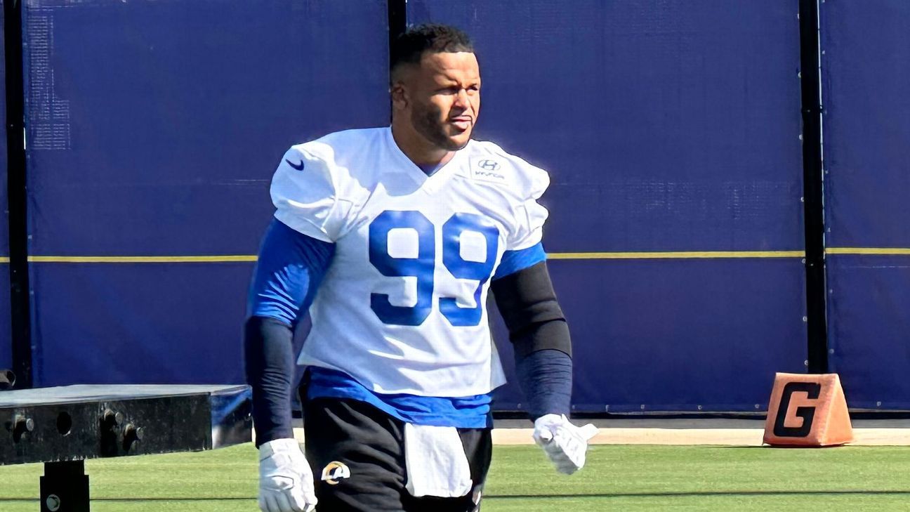 Football player wearing No. 99 jersey and gloves stands on a field near a goal marker.