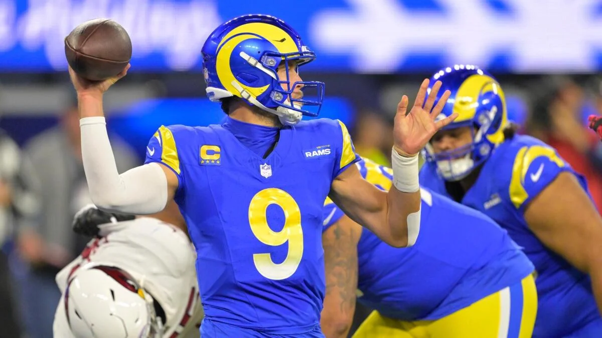 Quarterback in blue and yellow Rams uniform throws a football during an NFL game