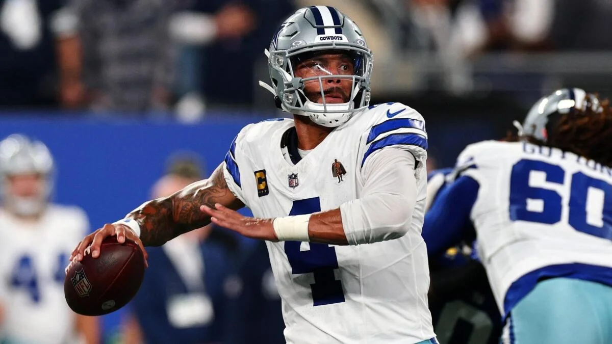 Dallas Cowboys quarterback in uniform prepares to throw during an NFL game.