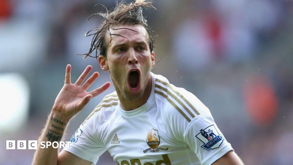 Footballer in a white jersey shouting with one hand raised during a match