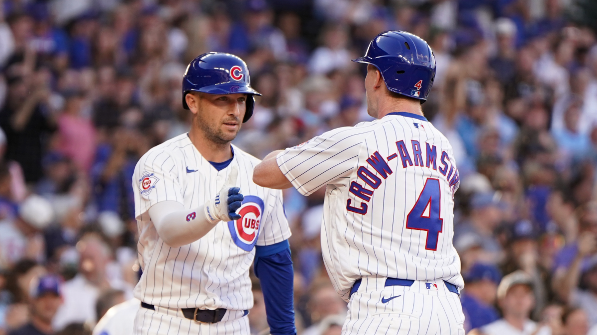 Two Chicago Cubs players in pinstriped uniforms celebrate with a fist bump during a game.