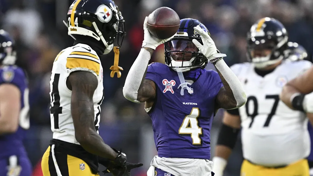 Baltimore Ravens player wearing number four catches a football against Pittsburgh Steelers defenders.