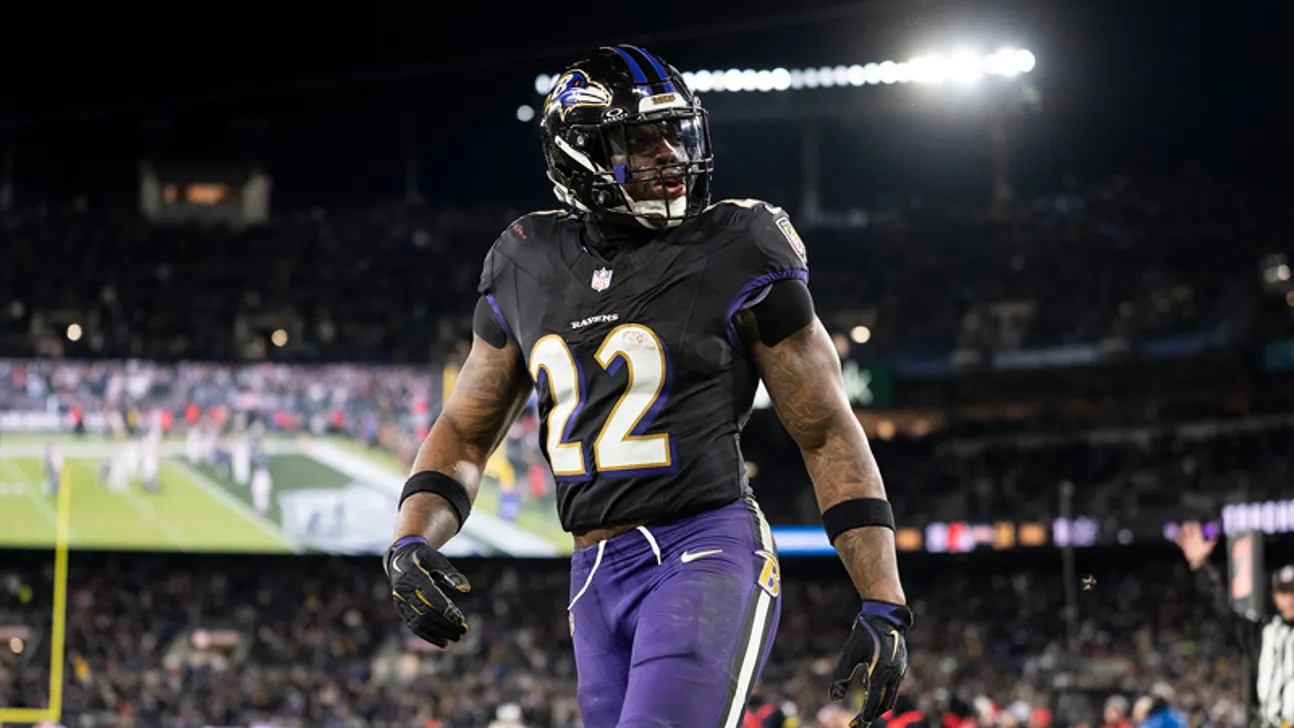 Baltimore Ravens player wearing number 22 uniform walks on a football field under stadium lights