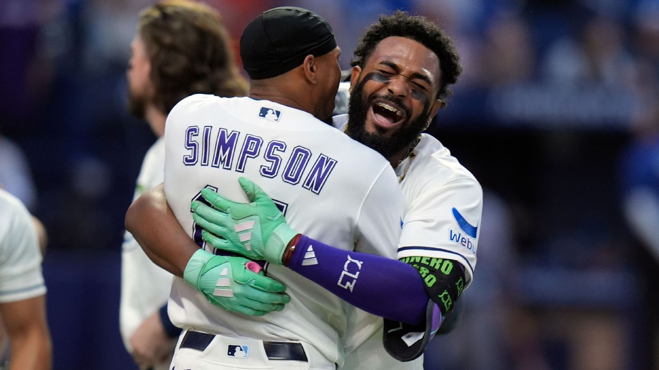Two Tampa Bay Rays players embrace and celebrate on the baseball field after a game.
