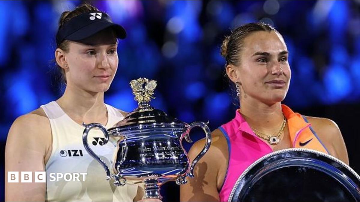Two tennis players pose beside large silver trophies during a presentation ceremony