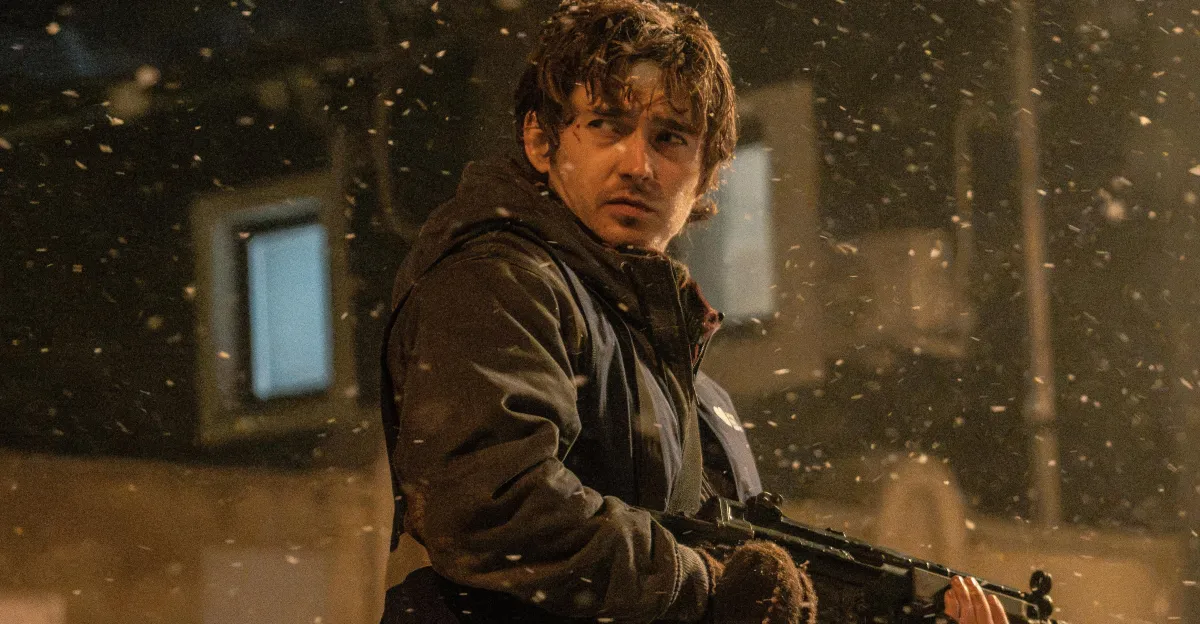 Wet-haired man in dark clothing holds a rifle amid swirling debris at night