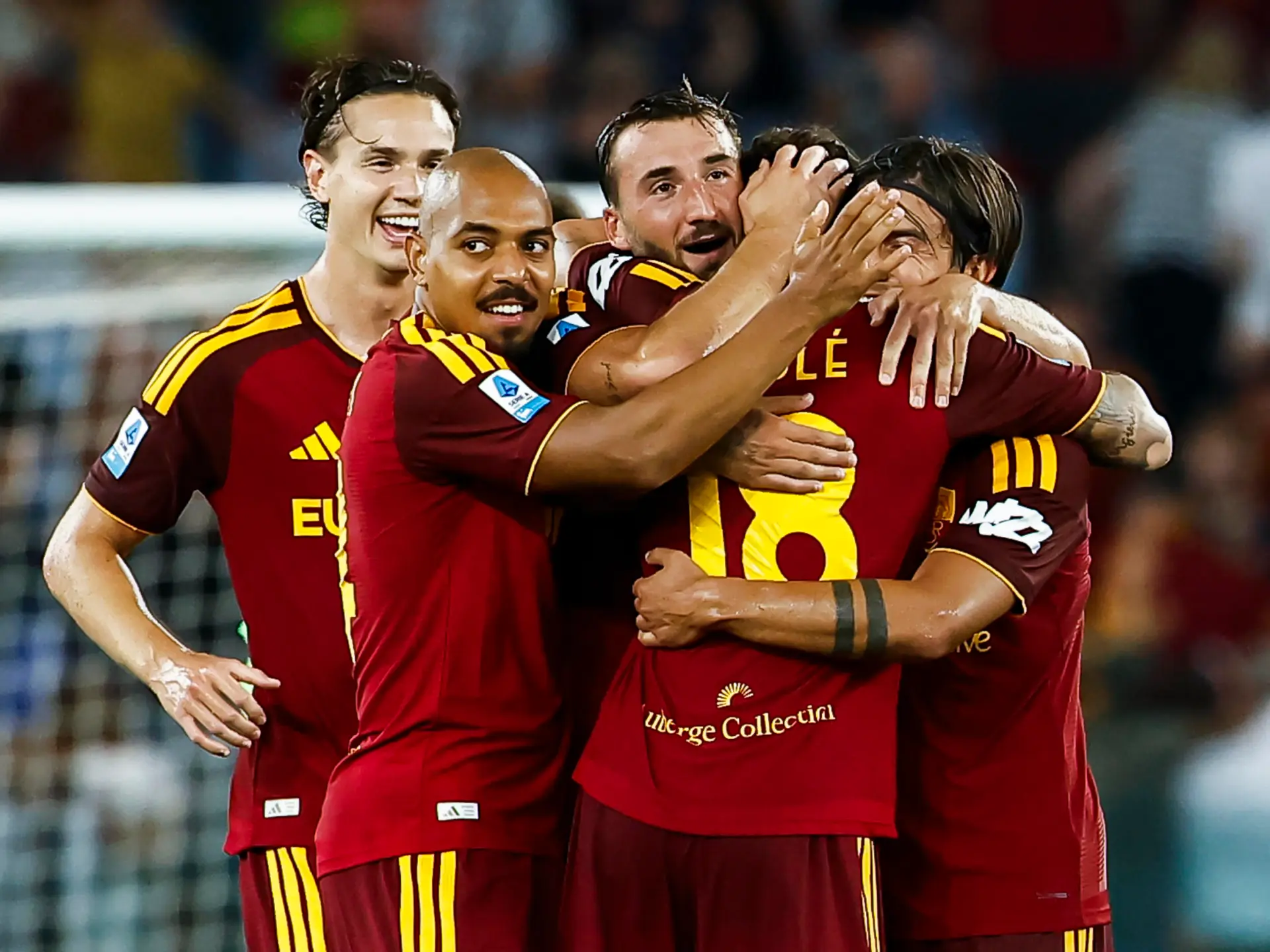Roma football players in red and yellow kits celebrate together during a match