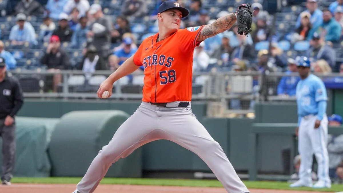 Houston Astros pitcher in orange jersey throws a baseball during an MLB game.