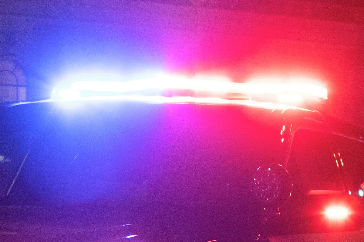 Flashing red and blue emergency lights illuminate the dark front of a vehicle at night