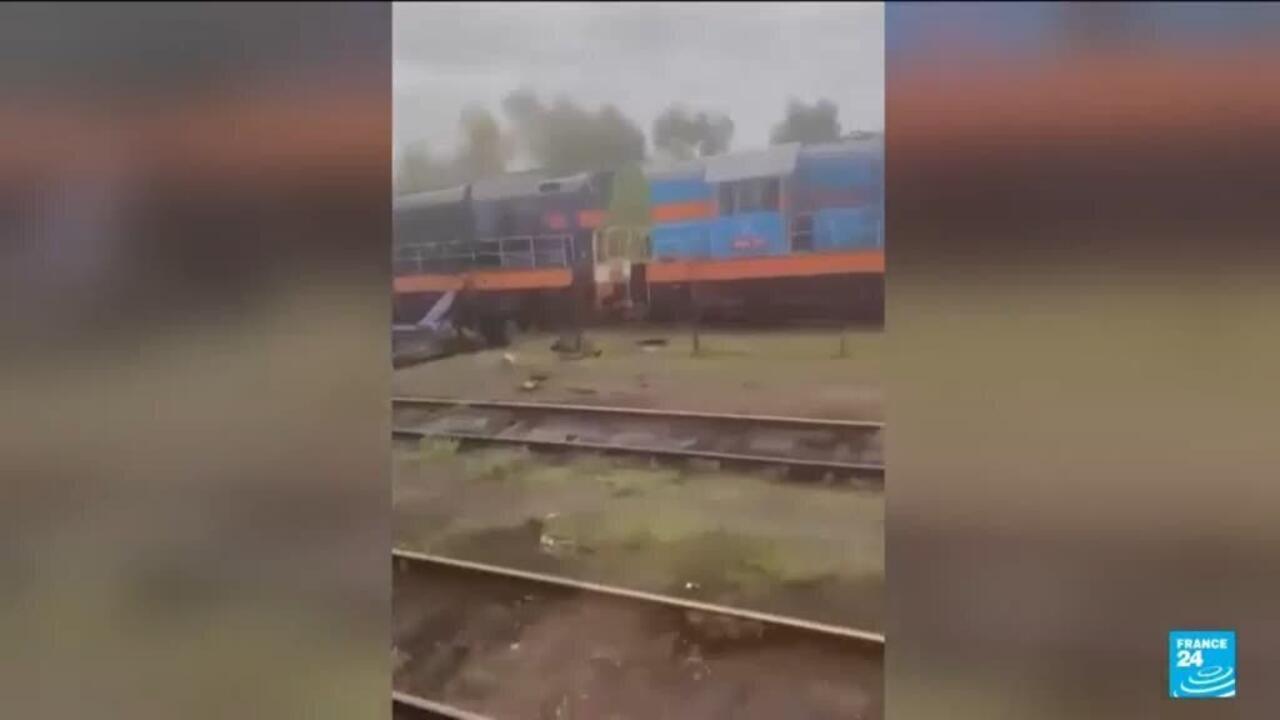 Rainy view of railway tracks and a blue-and-orange train or platform structure.