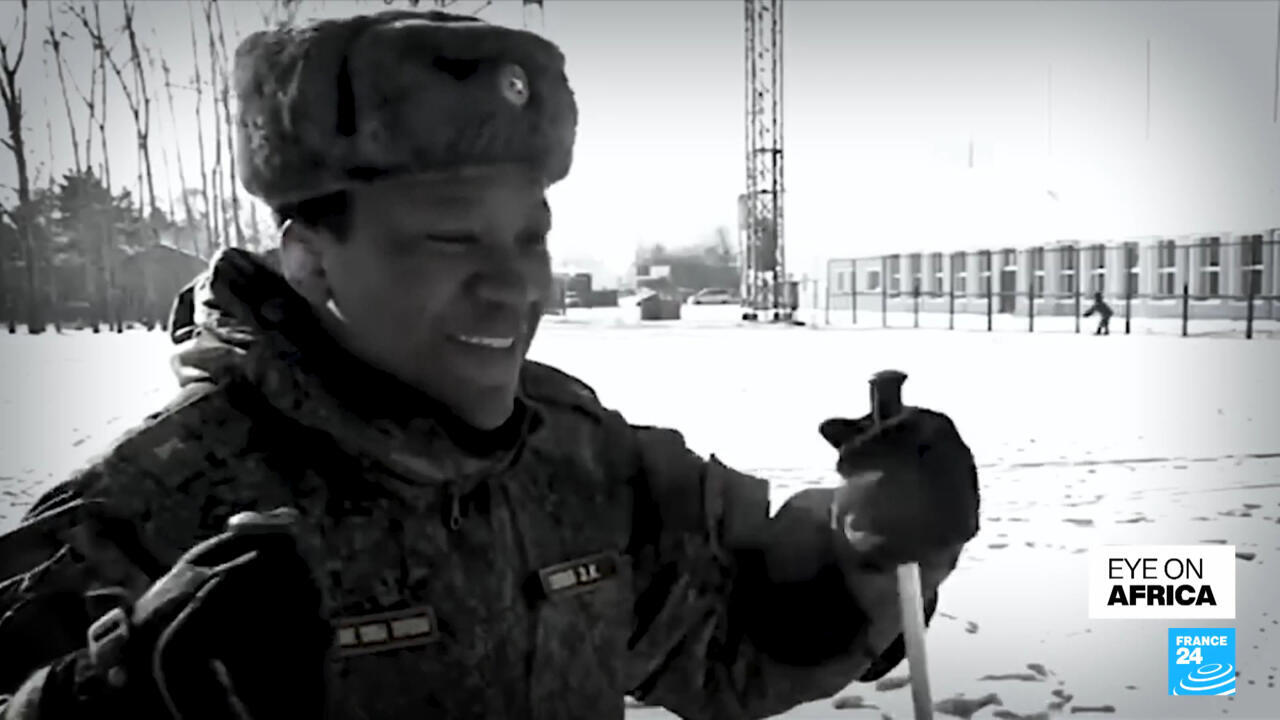 Black-and-white image of a soldier in winter camouflage holding a shovel in snowy surroundings.