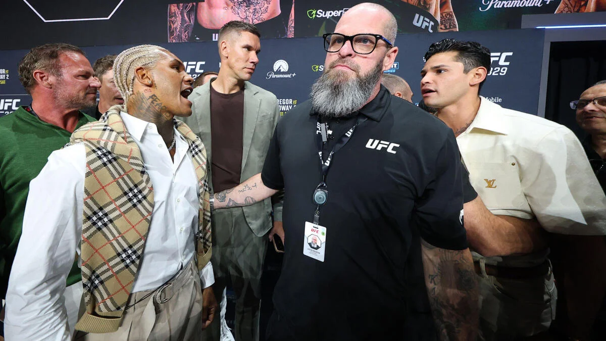 Two fighters stand among UFC officials and spectators at a crowded event