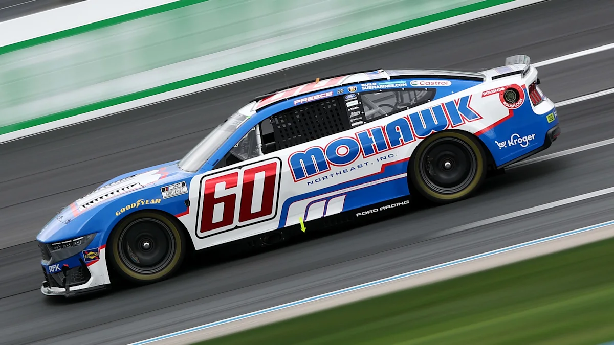 Blue and white No. 60 Mohawk stock car racing on a paved track, with motion blur.