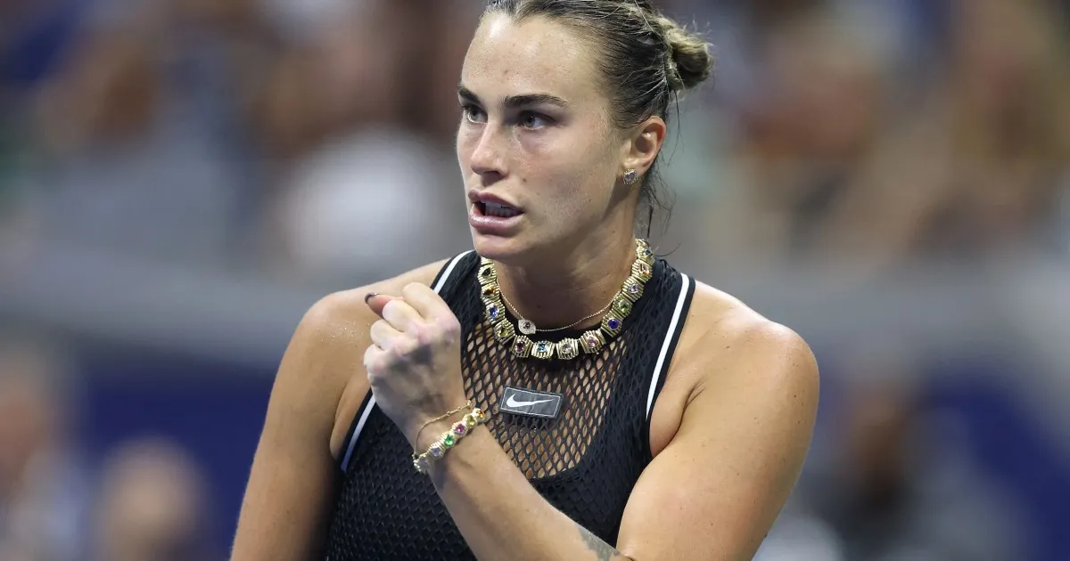 Female tennis player in black top clenches her fist during a match