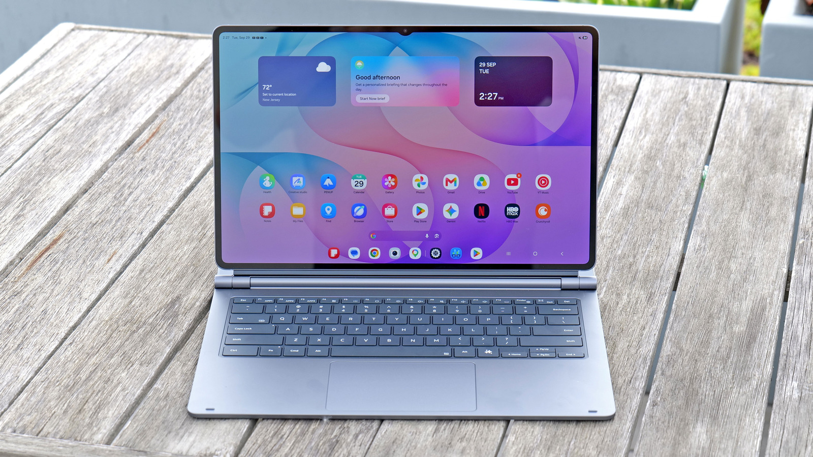 Samsung tablet with keyboard cover open on a weathered wooden outdoor table.