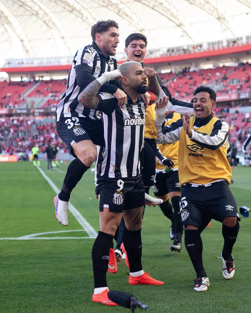 Santos players celebrate together on the pitch during a match at a stadium.