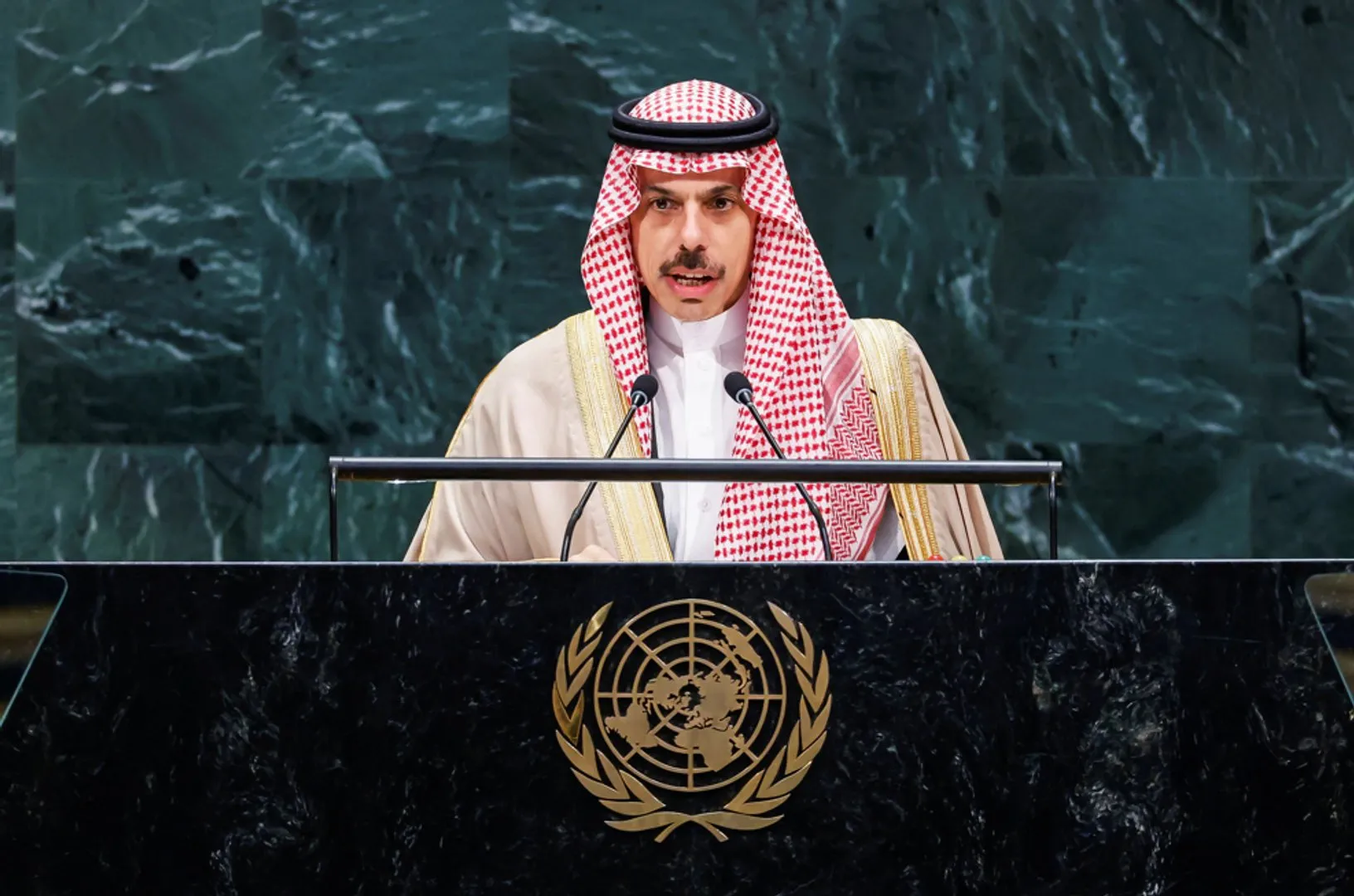 A man in traditional Saudi attire speaks at a lectern bearing the United Nations emblem.