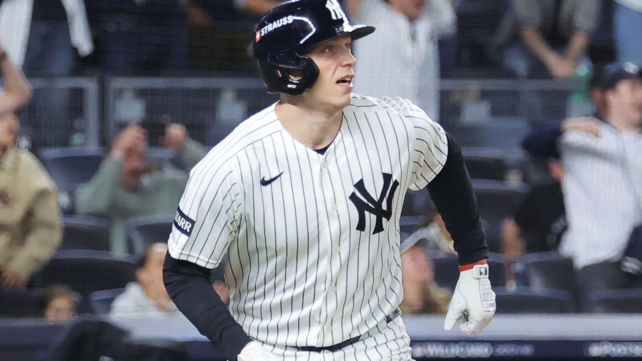 Yankees player in a pinstriped uniform and batting helmet runs on the field during a game.