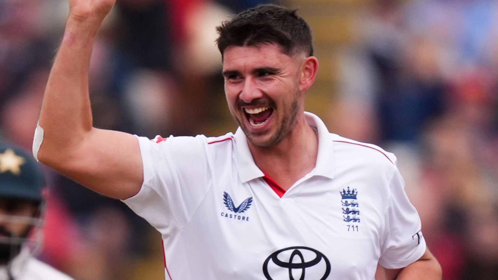 England cricketer in white shirt raises his arm and celebrates during a match