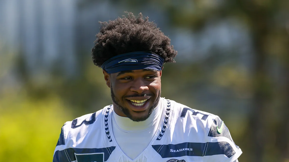 Smiling Seattle Seahawks football player wearing a blue headband and white uniform outdoors