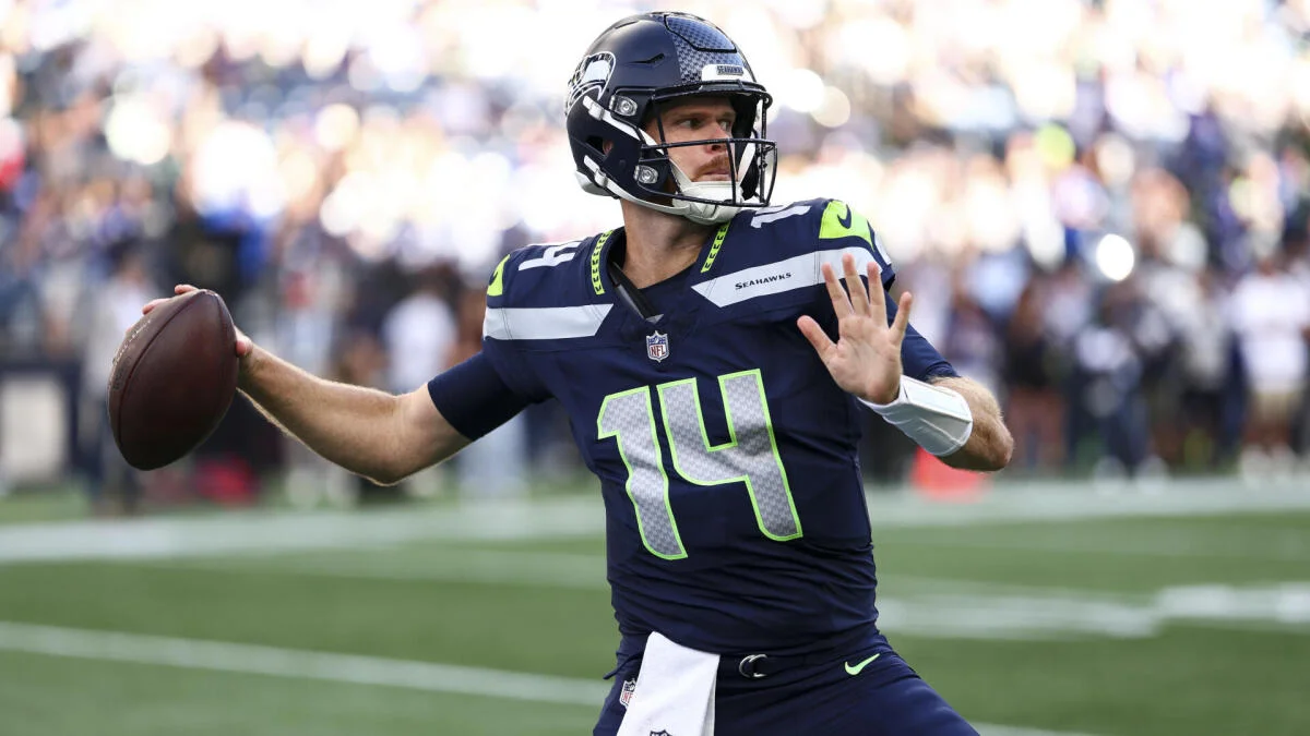 Football quarterback in Seahawks uniform prepares to throw during a game.
